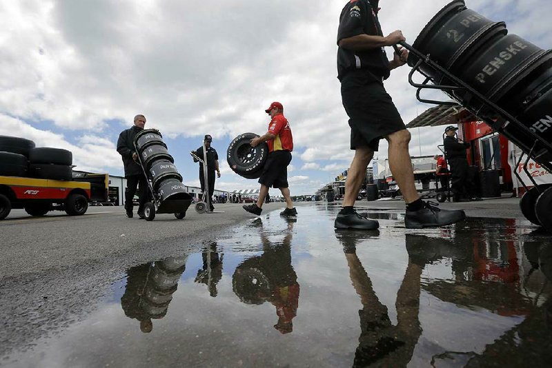 Sebastian Saavedra's crew member, Mike Briggs, center, of Indianapolis, carries race tires in the garage area as crews prepare for Sunday's Pocono IndyCar 500 auto race on Friday, July 4, 2014, in Long Pond, Pa. (AP Photo/Mel Evans)