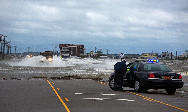 Nags Head police block the traffic leading to Manteo, N.C. as emergency high clearance vehicle passes through the roadway and wind from the Hurricane Arthur pushes the sound water in south of Nags Head, N.C., Friday, July 4, 2014. Arthur struck North Carolina as a Category 2 storm with winds of 100 mph late Thursday, taking about five hours to move across the far eastern part of the state. (AP Photo/The Virginian-Pilot, Hyunsoo Leo Kim)