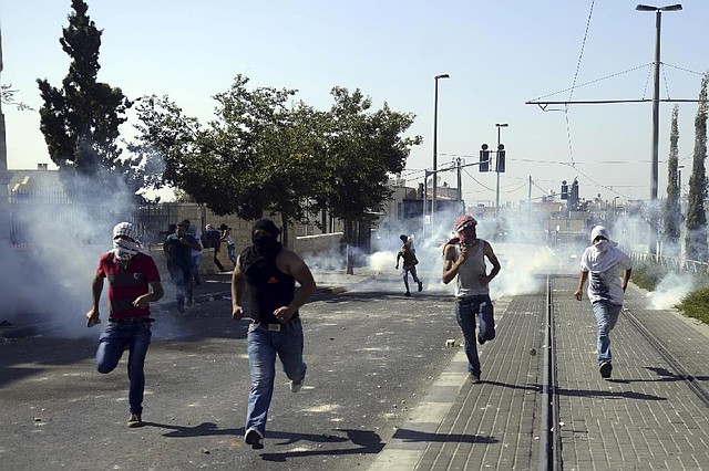 Palestinians run away from tear gas as they clash with Israeli security forces during the funeral of 16-year-old Mohammed Abu Khdeir in Jerusalem on Friday, July 4, 2014. Israeli police clashed with Palestinian protesters in Jerusalem on Friday as thousands of people converged on a cemetery for the burial of an Arab teenager, who Palestinians say was killed by Israeli extremists in a suspected revenge attack. (AP Photo/Mahmoud Illean)