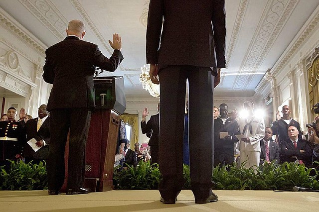 Deputy Homeland Security Secretary Alejandro Mayorkas (left onstage), accompanied by President Barack Obama (right), administers the oath of allegiance Friday during a naturalization ceremony for active-duty service members and civilians in the East Room of the White House.