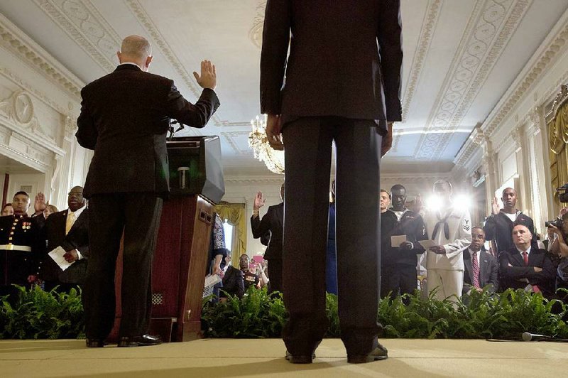 Deputy Homeland Security Secretary Alejandro Mayorkas (left onstage), accompanied by President Barack Obama (right), administers the oath of allegiance Friday during a naturalization ceremony for active-duty service members and civilians in the East Room of the White House.