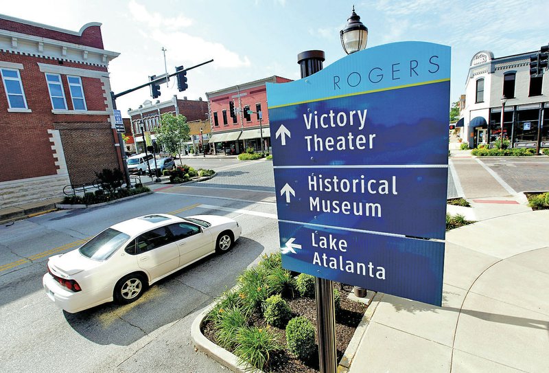 STAFF PHOTO JASON IVESTER Traffic passes a &#8220;wayfinding&#8221; sign at the intersection of Second and Walnut streets on June 27 in downtown Rogers.