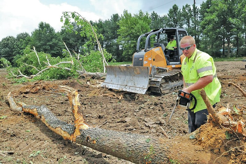 STAFF PHOTO FLIP PUTTHOFF Tommy Wallace, right, with the Rogers Street Department, clears land for additional soccer fields on Tuesday at Veterans Park in Rogers. The land is on the south side of the park.