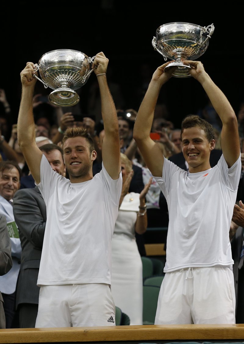 Vasek Pospisil of Canada, right, and Jack Sock of the U.S hold up their trophies after defeating Bob Bryan and Mike Bryan of the U.S in the men's doubles final at the All England Lawn Tennis Championships in Wimbledon, London, Saturday July 5, 2014.