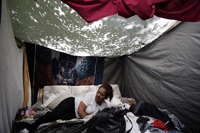 In this June 3, 2014 photo, Maria Esther Salazar rests inside her tent in the Jungle, a homeless encampment in San Jose, Calif. A homeless person can cost an estimated $60,000 a year, including trips to the emergency room and jail. The cost of housing someone can be just $16,000 a year. (AP Photo/Marcio Jose Sanchez)