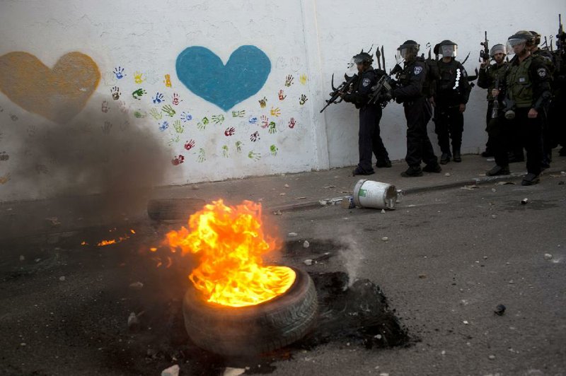 Israeli riot police officers take positions during clashes with Palestinians at the northern Arab Israeli town of Ar'ara, Saturday, July 5, 2014. Clashes between Israeli police and Palestinian protesters spread from Jerusalem to Arab towns in northern Israel Saturday, following the funeral of an Arab teenager who Palestinians say was killed by Israeli extremists in a revenge attack. (AP Photo/Oded Balilty)