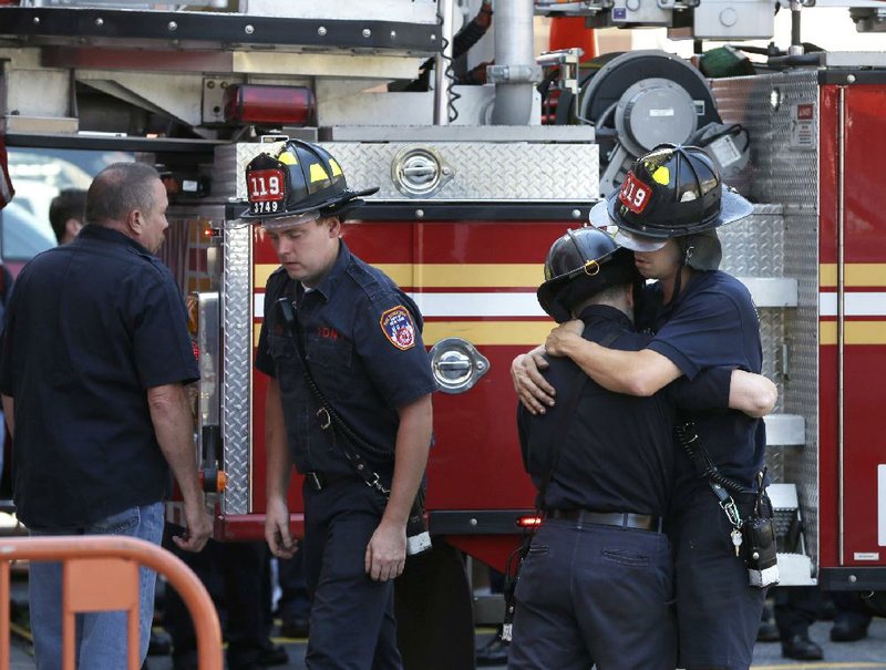 Firefighters hug one another after hanging bunting over the firehouse in honor of Lt. Gordon Ambelas in New York, Sunday, July 6, 2014. The Fire Department of New York is mourning the death of Ambelas, who became trapped while looking for victims in a public-housing high-rise blaze, the first to die in the line of duty in more than two years. Ambelas died Saturday after suffering multiple injuries while on the 19th floor of the 21-story building in the Williamsburg section of Brooklyn, officials said. (AP Photo/Seth Wenig)