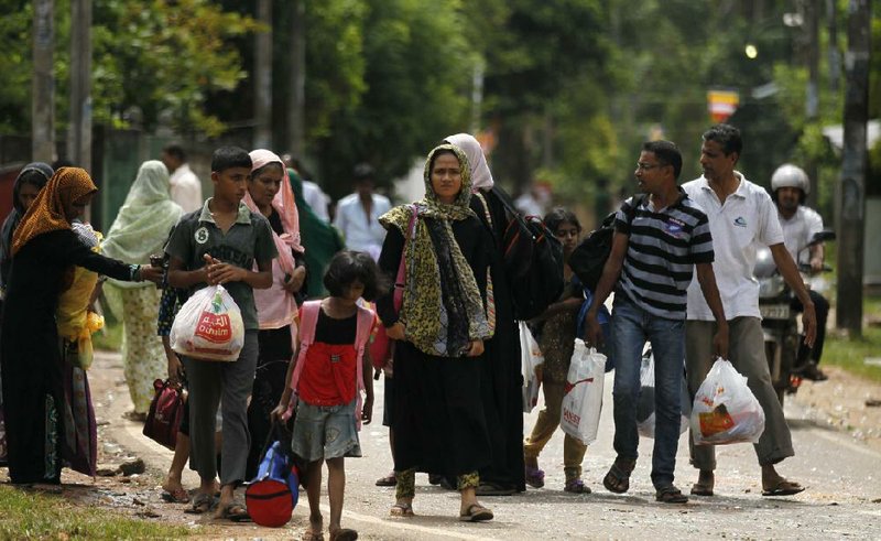 FILE - In this Monday, June 16, 2014 file photo, Sri Lankan Muslims walk to safer places following attacks by hard-line Buddhist group Bodu Bala Sena in Aluthgama, 50 kilometers (31 miles) south of Colombo, Sri Lanka. The European Union says it is very alarmed by the violence perpetrated against Muslims in Sri Lanka in which three people were killed and more than 50 wounded. The EU delegation in Colombo issued a statement that urged the Sri Lankan government to ensure that the rule of law is upheld. (AP Photo/Eranga Jayawardena, File)