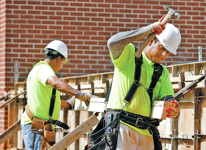 STAFF PHOTO DAVID GOTTSCHALK Juan Garcia, right, and Jaime Vargas, both with Advanced Concrete Services of Fayetteville, build a form Tuesday for the extension to West Fork Middle School.