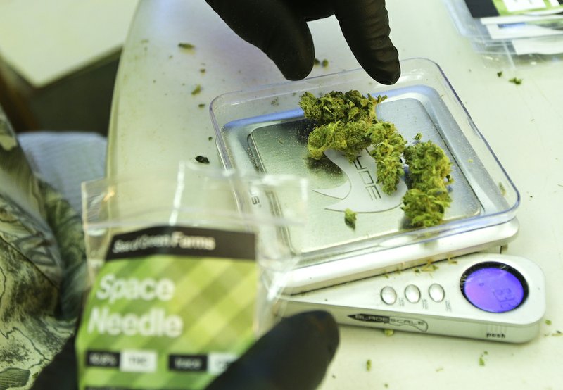In this photo taken Tuesday, July 1, 2014, a worker weighs out one-gram packets of a variety of recreational marijuana named "Space Needle," during packaging operations at Sea of Green Farms in Seattle. The grower, the first business licensed to grow recreational marijuana in Washington state, worked all weekend to have supplies ready for stores that were expected to be granted sale licenses on Monday, July 7, the day before legal recreational pot sales begin on July 8. 