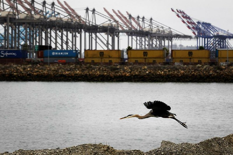 Bloomberg Photo Service 'Best of the Week': A bird flies as shipping containers stand on rail lines at the Port of Los Angeles in San Pedro, California, U.S., on Monday, June 30, 2014. A six-year labor contract expiring between about 20,000 dockworkers and 29 West Coast ports threatens to disrupt trade as negotiators scramble to forge an agreement on salaries and health-care costs. Photographer: Patrick T. Fallon/Bloomberg