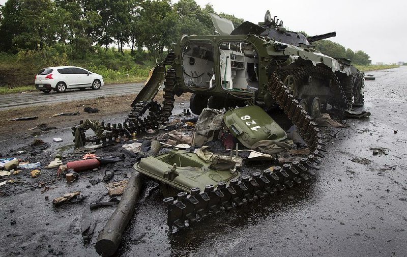 A car travels past a destroyed pro-Russian APC near the city of Slovyansk, Donetsk Region, eastern Ukraine Monday, July 7, 2014. Ukraine's president Petro Poroshenko has called the capture of the Pro-Russian separatist stronghold of Slovyansk a "turning point" in the fight for control of the country's east. (AP Photo/Dmitry Lovetsky)
