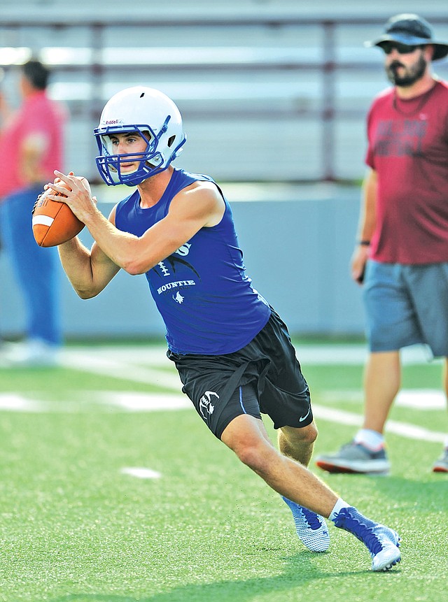 STAFF PHOTO ANDY SHUPE Cole Evans, Rogers High quarterback, rolls out to make a pass attempt while playing 7-on-7 Monday at Jarrell Williams Bulldog Stadium in Springdale.