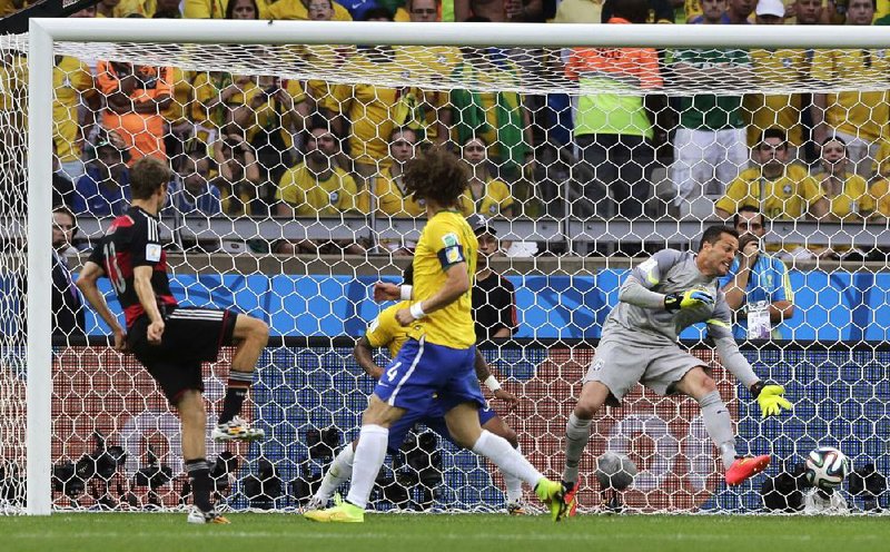 Germany’s Thomas Mueller (left) scores in the 11th minute despite the efforts of goalkeeper Julio Cesar (right) and David Luiz (4). Mueller was one of five Germans to score in a 7-1 victory over Brazil in the semifinal game.