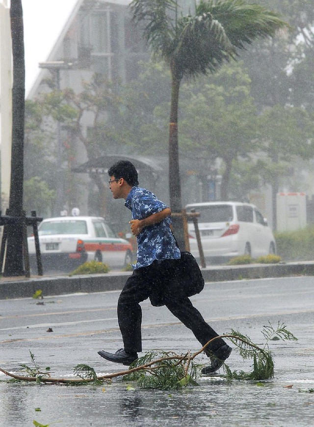 A man crosses a street amid strong winds from Typhoon Neoguri in Naha, Okinawa, southern Japan, on Tuesday.