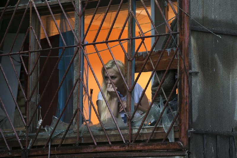 A woman looks through a broken window in her house after shelling Tuesday in Luhansk, eastern Ukraine.