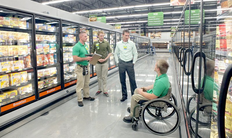 TIMES photograph by Annette Beard Timm King, Jaron Hartman visit with manager Scott McMillan and Dustin King Monday. All three were sporting the Neighborhood Market colors of green and khaki.