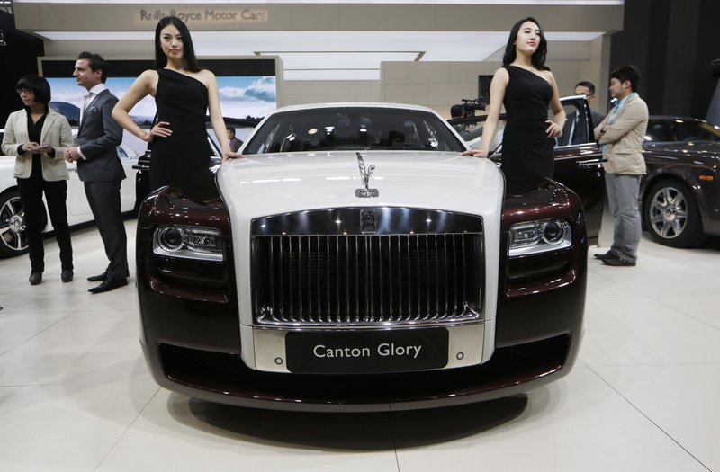 In this Nov. 21, 2013 file photo, models pose beside the Rolls-Royce Canton Glory at the company's booth during Guangzhou 2013 Auto Show in China's southern city of Guangzhou. Britain-based Rolls-Royce on Tuesday, July 8, 2014 said that global sales in the first half of the year were up 33 percent compared with the same period in 2013.