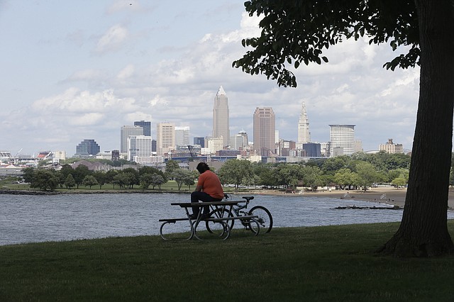 A man sits on a picnic table with a view of downtown Cleveland Tuesday, July 8, 2014. Cleveland won the unanimous backing of a Republican National Committee panel on Tuesday, all but guaranteeing the GOP's 2016 presidential pick will accept the party's nomination in perennially hard-fought Ohio.