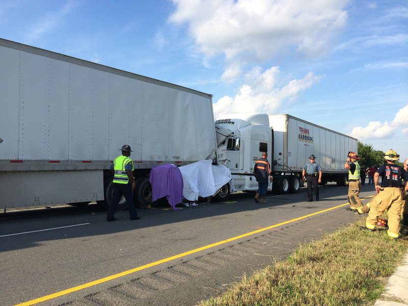 Emergency officials respond to the scene of an accident Wednesday afternoon on Interstate 40 involving three tractor-trailers and a white Cadillac.