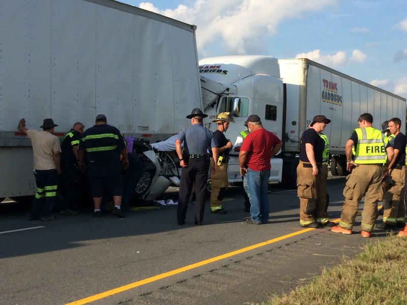 Emergency officials respond to the scene of an accident Wednesday afternoon on Interstate 40 involving three tractor-trailers and a white Cadillac.