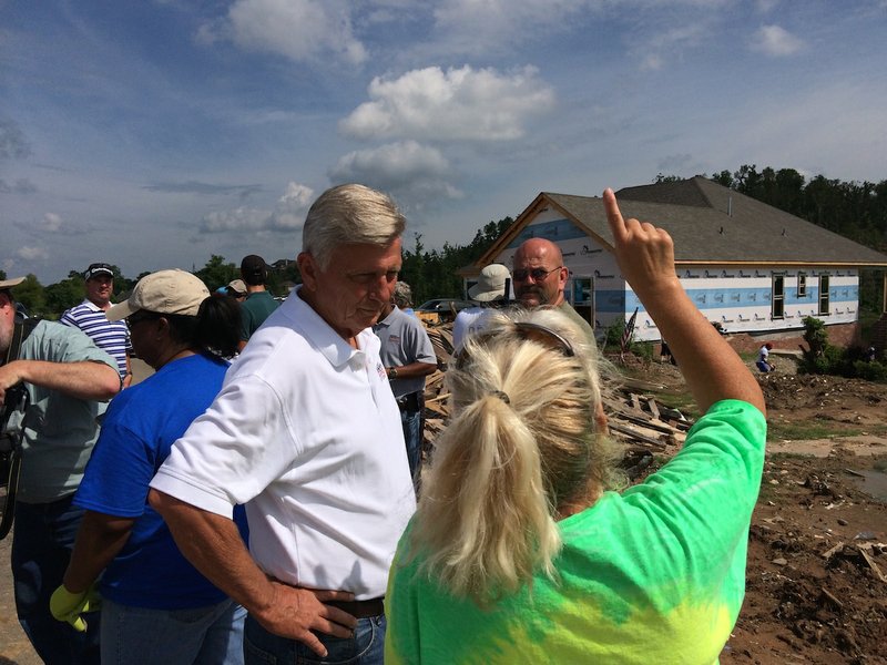 Gov. Mike Beebe speaks to Mayflower residents on Thursday while members of Beebe Cares help with tornado cleanup along River Bend Road. 