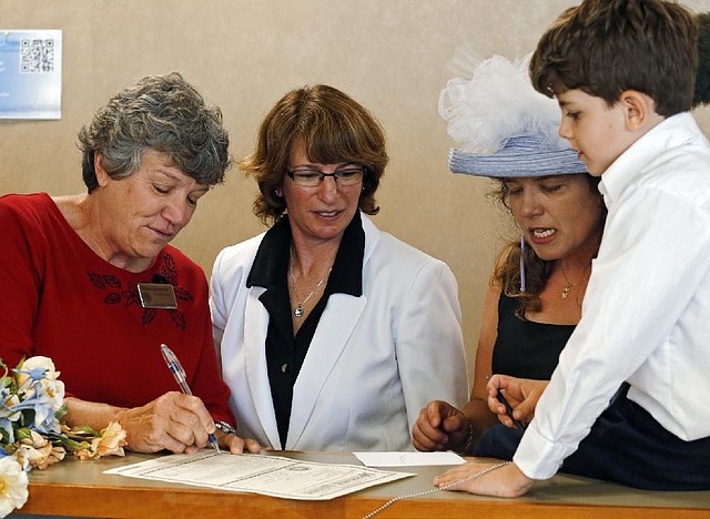 Denver County Clerk Debra Johnson (left) signs the marriage license of Fran and Anna Simon as their son Jeremy watches Thursday at the Denver clerk’s office.