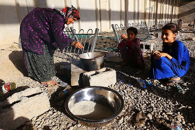 In this Wednesday July 9, 2014 photo, Iraqi refugees who fled from Mosul and other towns cook food at a temporary camp outside Irbil, northern Iraq, nearly a month after Islamic militants took over the country's second largest city. The lightning sweep by the insurgents over much of northern and western Iraq the past month has dramatically hiked tensions between the country's Shiite majority and Sunni minority. At the same time, splits have grown between the Shiite-led government in Baghdad and the Kurdish autonomy region in the north.