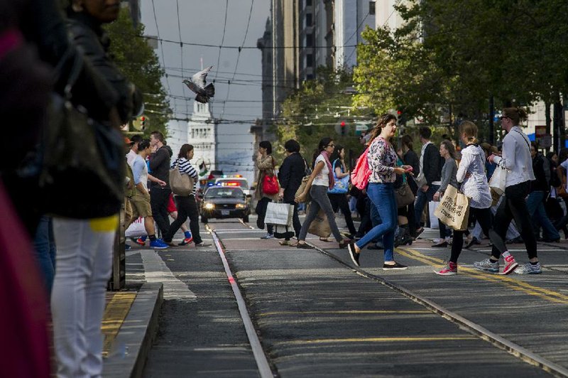 Pedestrians cross Market Street in a busy shopping area of San Francisco earlier this week. Business economists in a survey said they expect the U.S. economy grew at an annual rate of 3 percent in the second quarter on expectations that consumer spending set a more modest pace.