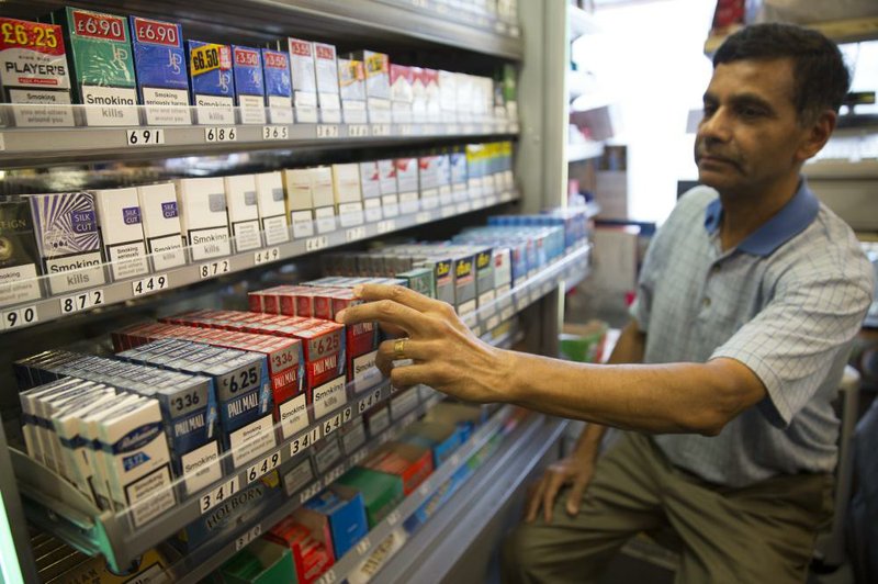 A shopkeeper reaches for a pack of British American Tobacco-made Pall Mall cigarettes Friday at a newsstand in London. British American Tobacco owns a 42 percent stake in Reynolds American Inc., the tobacco company in merger talks with cigarette maker Lorillard Inc.