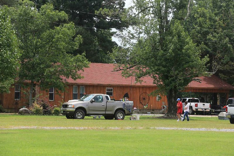 Arkansas Democrat-Gazette/RICK MCFARLAND--07/11/14--  People walk around a home early Friday afternoon where two bodies were found slain around 7 a.m. on Cowboy Ln in Pine Bluff Friday.