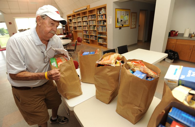 STAFF PHOTO ANDY SHUPE Joe Barber of Springdale collects bags of groceries for a recipient June 20 at St. Thomas Episcopal Church in Springdale. Barber, a church member, volunteered to help with the church&#8217;s first grocery giveaway. The grocery relief ministry will distribute food the third Friday of each month. The next food distribution is from 5 to 7 p.m. Friday.