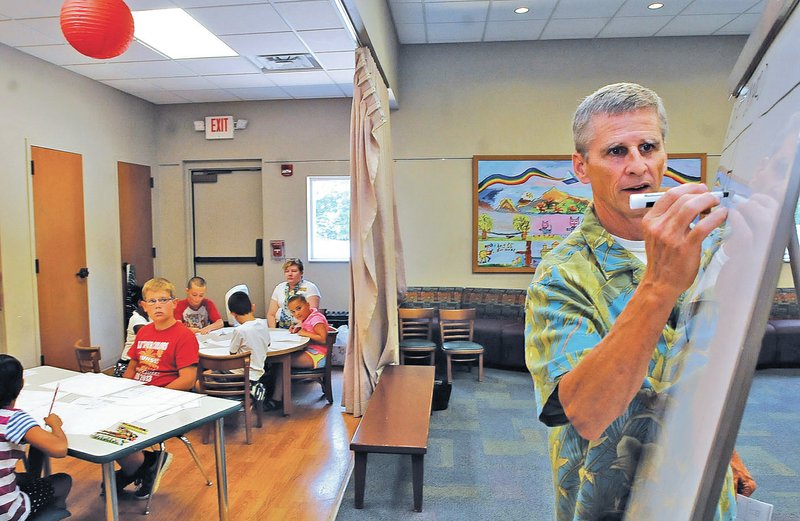 STAFF PHOTO FLIP PUTTHOFF Rich Davis starts a drawing lesson for children Friday at the Rogers Public Library. Davis is an artist whose work includes teaching drawing to children in schools and libraries.