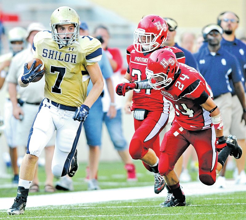 FILE PHOTO Chandler Smith, left, of Shiloh Christian races for a first down while pursued by Heber Springs&#8217; Dalton Darrell, right, and Geoffrey Anderson during the third quarter of the Saints&#8217; game Sept. 1, 2011, in the 2011 Hooten&#8217;s Kickoff at Reynolds Razorback Stadium in Fayetteville. A proposal the Arkansas Activities Association is considering this summer would move the start of the prep football season in Arkansas up one week starting in 2016.