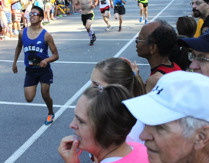 Arkansas Democrat-Gazette/FRANK FELLONE
With eyes glued to the finish-line clock, spectators look ahead of Jose Castelano, 15, of Dardanelle, who held a 5:05-minute-per-mile pace in the 2014 Go! Mile footraces in North Litle Rock's Burns Park on June 14.