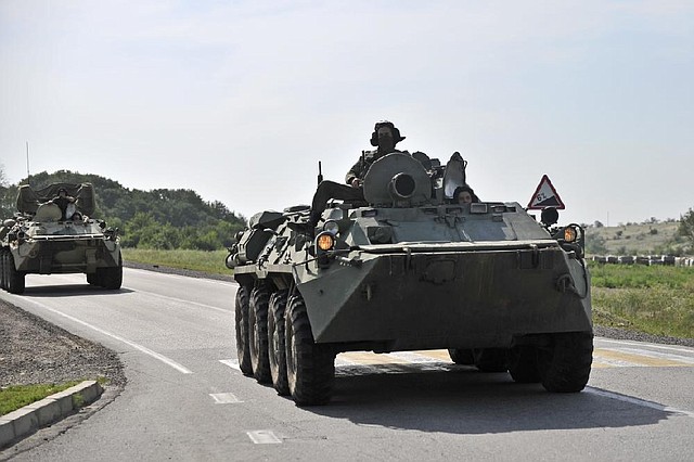 Two Russian armored personal carriers roll near the border with Ukraine outside the Russian town of Donetsk in Rostov-on-Don region, Sunday, July 13, 2014. Russia's foreign ministry said Sunday that a Ukrainian shell hit a town on the Russian border, killing one person and seriously injuring two others. But Ukraine denied firing a shell into Russian territory. (AP Photo/Sergei Pivovarov)