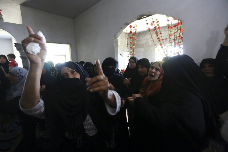 Palestinian mourners cry in a house after the bodies of Mousa Abu Muamer, 56, and his son Saddam, 27, who were killed in an overnight Israeli missile strike at their house in the outskirts of the town of Khan Younis, southern Gaza Strip, were brought in during their funeral procession on Monday, July 14, 2014. Saddam's wife, Hanadi, 27, was also killed in the attack. 