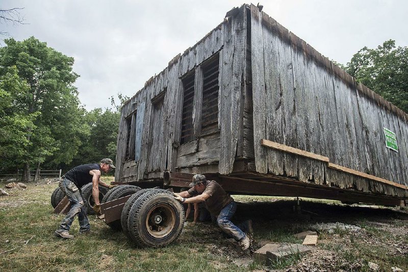STAFF PHOTO ANTHONY REYES @NWATONYR
Mathew Collins, left, and Ronnie Howard, both with Howard House-Moving of Dora, Mo., move the trailer wheels Monday, July 14, 2014 from under the former post office and general store the Glade community on a property near Garfield. The building was moved from it's original location which was flooded out when the Beaver Dam was built to a farm in Pea Ridge. It's new location is next to the Coal Gap School.