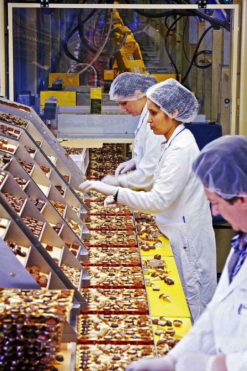 Employees check boxes of Lindt chocolates after they are packaged by robots inside the Lindt & Spruengli AG factory in Kilchberg, near Zurich, Switzerland, on Tuesday, Aug. 2, 2011. Lindt & Spruengli AG are the world's largest maker of premium chocolate. Photographer: Gianluca Colla/Bloomberg