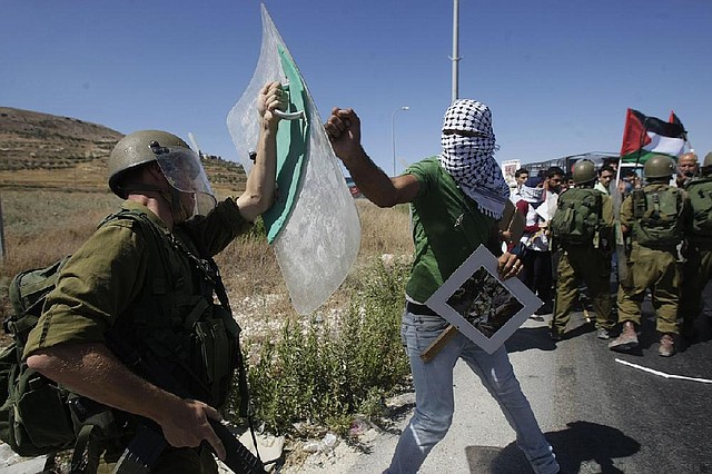 A Palestinian confronts an Israeli soldier (left) during a demonstration against Israeli military action in Gaza, near the West Bank town of Nablus, July 14, 2014. 