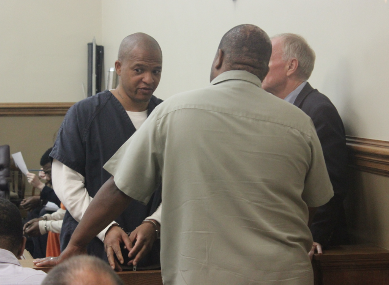 Darrell Dennis left, speaks with a family member before a hearing Tuesday.