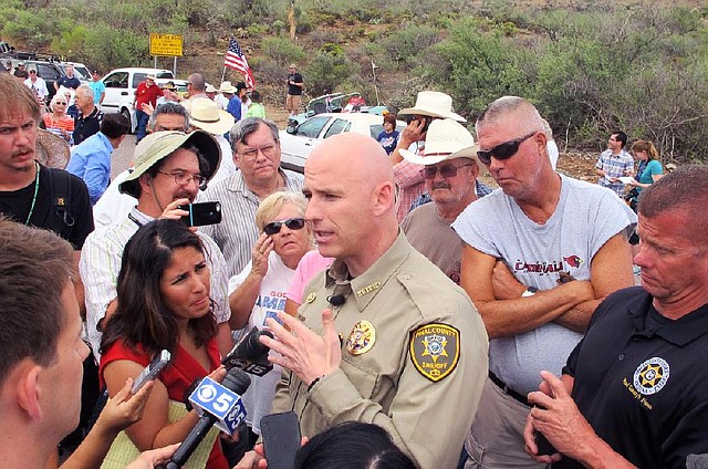 Pinal County Sheriff Paul Babeu talks to reporters as protesters gather near the entrance to a juvenile facility to stop a busload of Central American children from being delivered to the facility Tuesday in Oracle, Ariz. Federal officials delayed the bus with no details on whether the children will arrive or not.