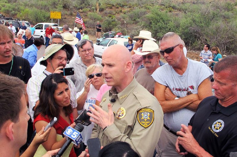 Pinal County Sheriff Paul Babeu talks to reporters as protesters gather near the entrance to a juvenile facility to stop a busload of Central American children from being delivered to the facility Tuesday in Oracle, Ariz. Federal officials delayed the bus with no details on whether the children will arrive or not.