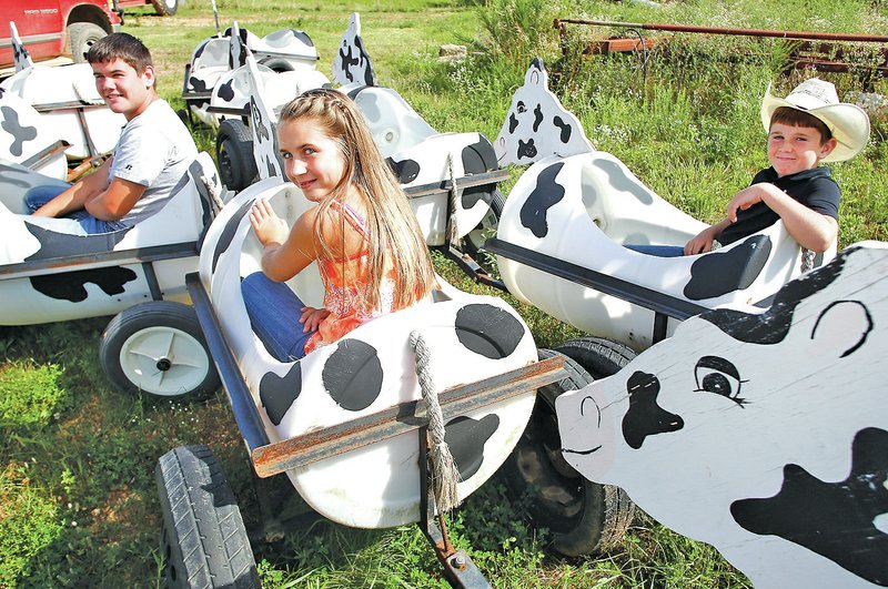 STAFF PHOTO DAVID GOTTSCHALK Garrett Hays, 13, from left, Emily Hays, 11, and Ty Hays, 9, sit in part of the cow train on their farm in Springtown.