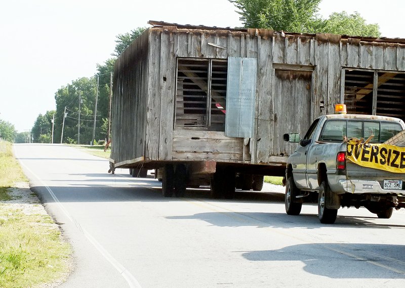 TIMES photographs by Annette Beard &#8220;Wide load&#8221; across the back of the pickup truck following the Glade Store and Post Office warned other drivers. The building was pulled slowly around the corner of Arkansas Highway 72 and Twelve Corners Road at the beginning of the journey.