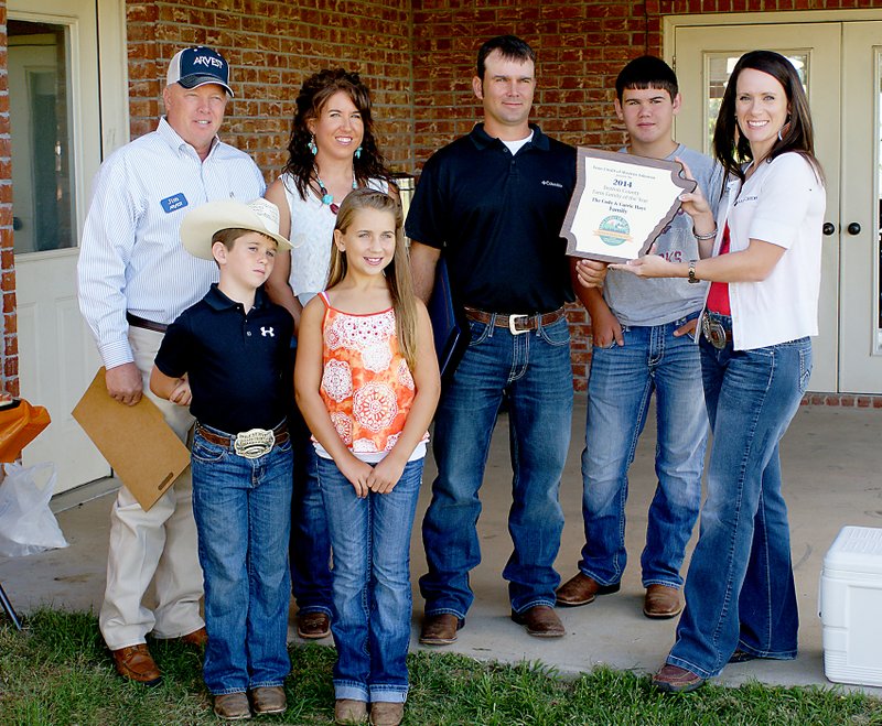 Photo by Randy Moll Recipients of the 2014 Benton County Farm Family of the Year Award were Cody and Carrie Hays and their children &#8212; Ty, 9; Emily, 11; and Garrett, 13. The Award was presented at the Hays family farm, south of Springtown, on Tuesday. Jim Singleton, of Arvest Bank and chairman of the Benton County Farm Family selection committee (left), served as master of ceremonies. Savannah Dickinson, vice president of Farm Credit Services (right), presented the award. Proclamations were read from the offices of county judge Bob Clinard, state representative Dan Douglas, and U.S. congressman Steve Womack. For a full story, see next week&#8217;s issue of the Eagle Observer.