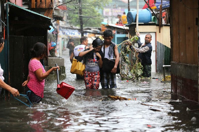 People return home Wednesday in Quezon, north of Manila, Philippines, as water from Typhoon Rammasun covers the streets. The storm, while weaker than expected, caused dozens of deaths and widespread power disruptions.