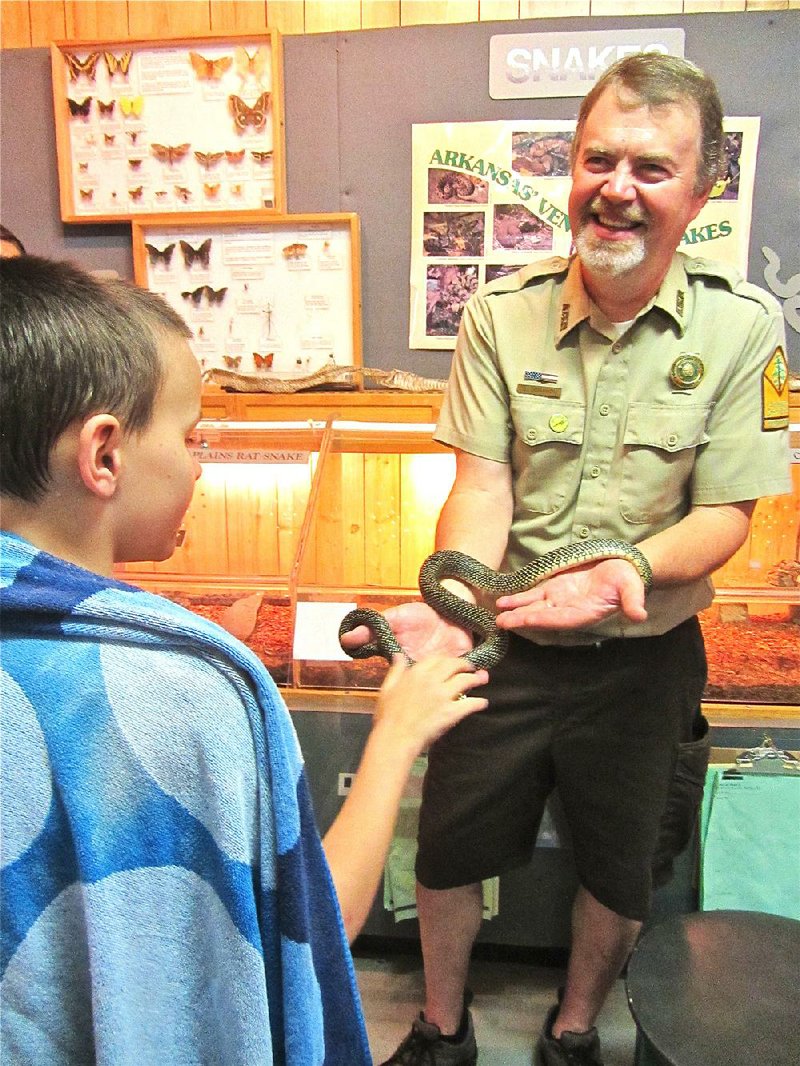 At Lake Catherine State Park, park interpreter Steve Donahou shows speckled king snake Elvis to a visitor just in from swimming and wrapped in a towel.