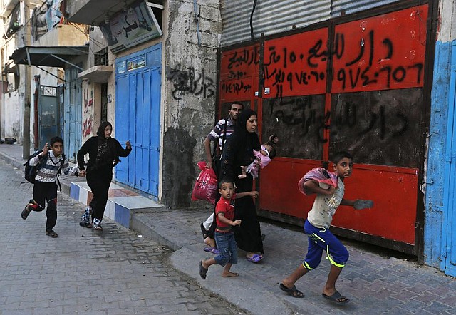 Palestinians run for shelter Wednesday in Gaza City as explosions are heard in the distance after Israeli aircraft dropped leaflets warning residents to flee the area.