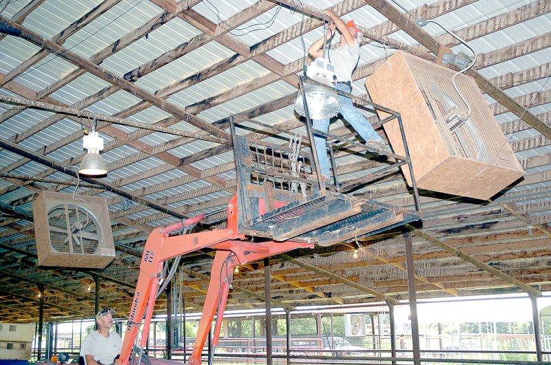 RICK PECK MCDONALD COUNTY PRESS Jacob Pierce hangs a new light fixture over the show arena while Scott Huston does the heavy lifting at Monday&#8217;s cleanup and work day in preparation of the 40th annual McDonald County Fair at McDonald County High School that began today.